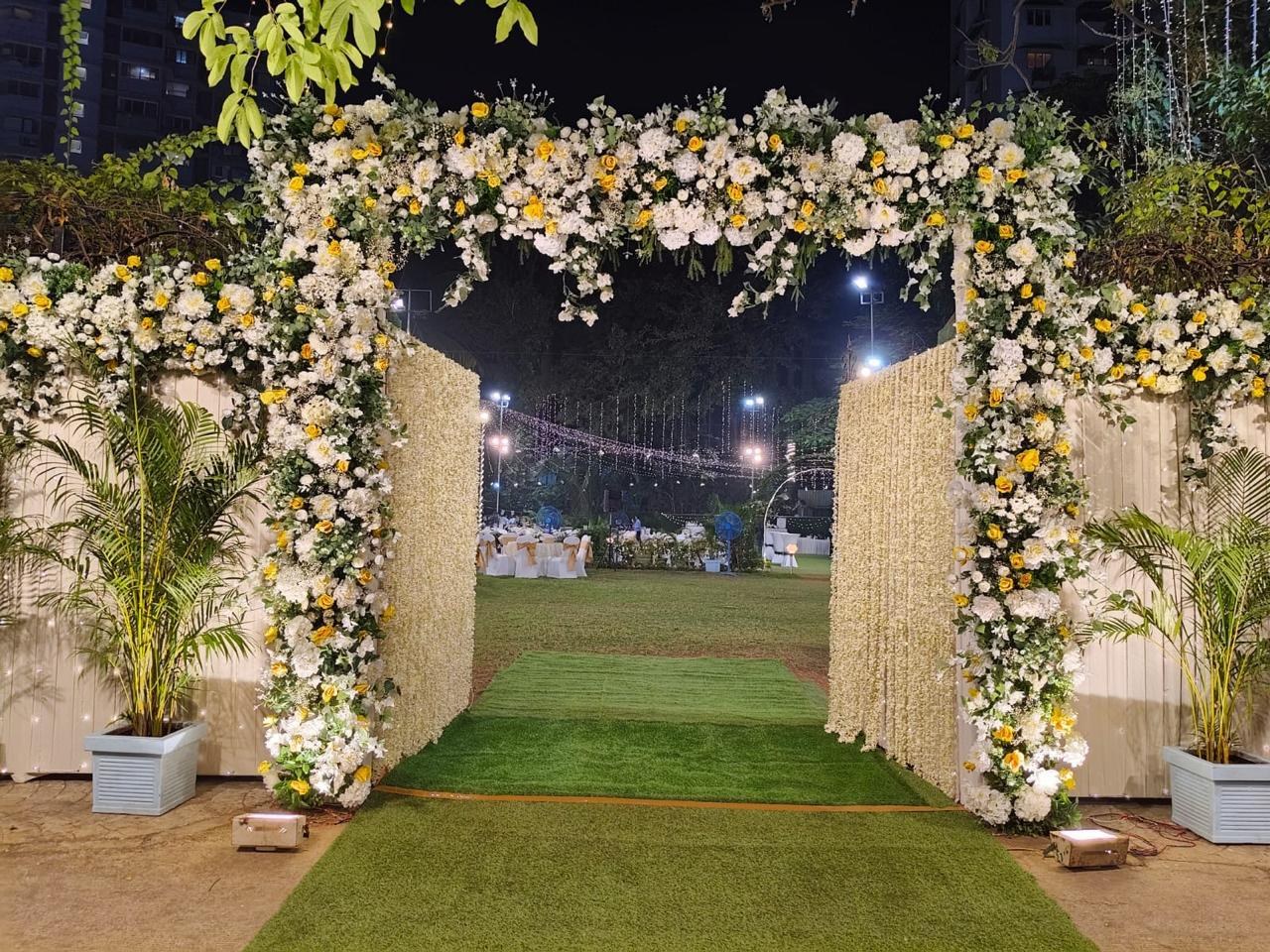Grand floral entrance arch leading into an outdoor celebration